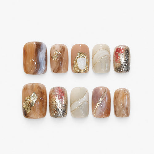catalog: Short square press-on nails in marbled amber, toffee and ivory tones with gold foil flakes and a sculpted gold frame accent.