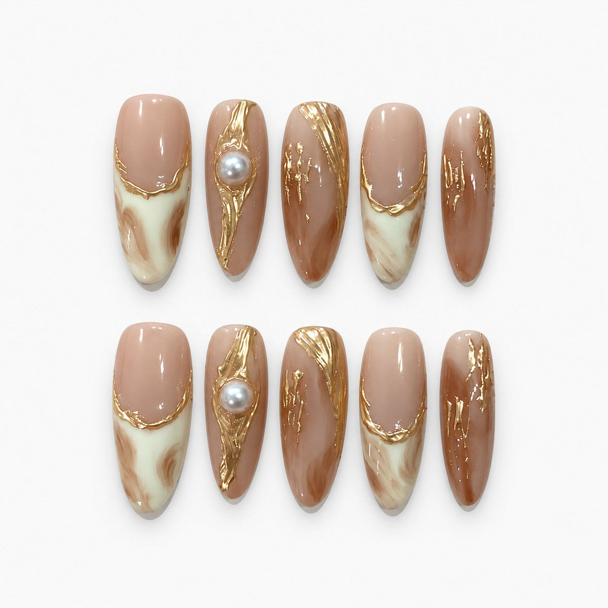 catalog: Long almond press-on nails in warm nude with cream and caramel marbling, raised gold foil lines, and a single cream pearl accent.