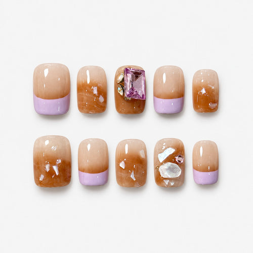catalog: Short square press-on nails in warm amber with lilac French tips, shell flecks and a pink rectangular gem.