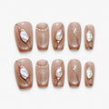 catalog: Medium coffin press-on nails in warm nude with bronze cat-eye shimmer, raised clear swirls, opal stones and a row of small pearls.