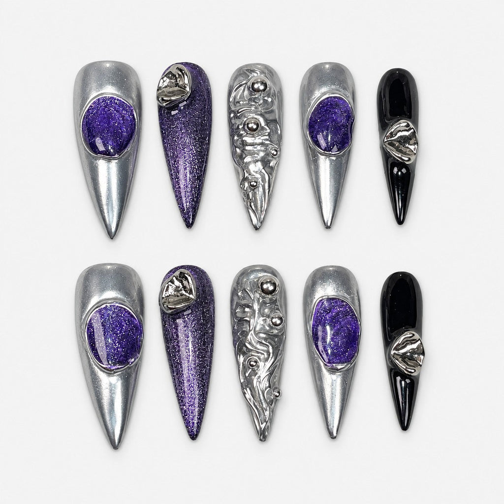 catalog: Long stiletto press-on nails in mirror silver chrome with deep purple glitter stones, sculpted silver ripples with metal beads, and two glossy black accent nails.
