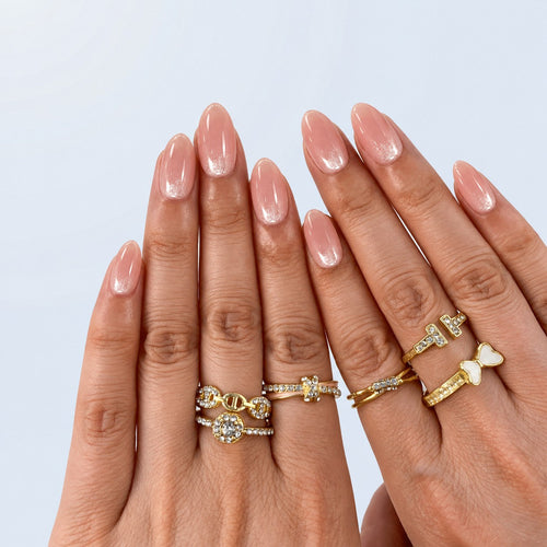 hand: Short almond nails in sheer pink nude with glossy finish and shimmering pale champagne French tips.