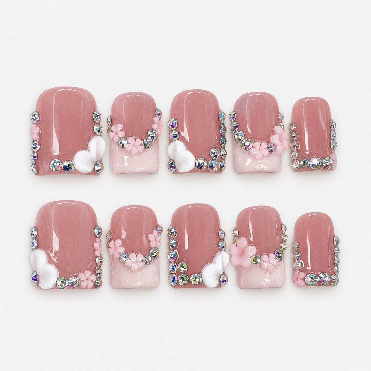 catalog: Medium square press-on nails in dusty rose with a milky pink French tip, rhinestone clusters, sculpted pink flowers and white hearts.