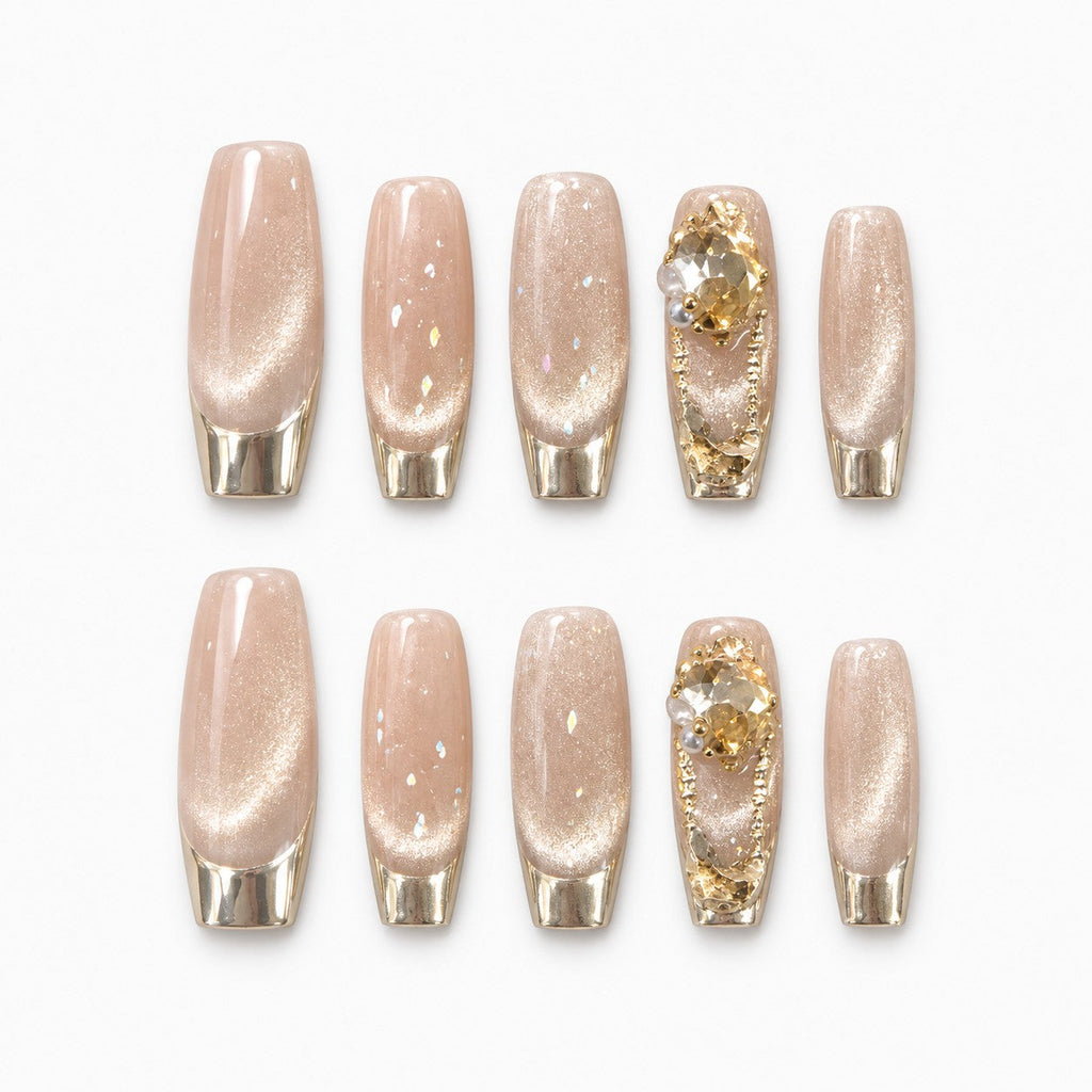 catalog: Long coffin press-on nails in shimmering champagne with gold chrome French tips and raised gold gem accents.