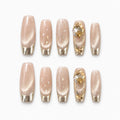 catalog: Long coffin press-on nails in shimmering champagne with gold chrome French tips and raised gold gem accents.