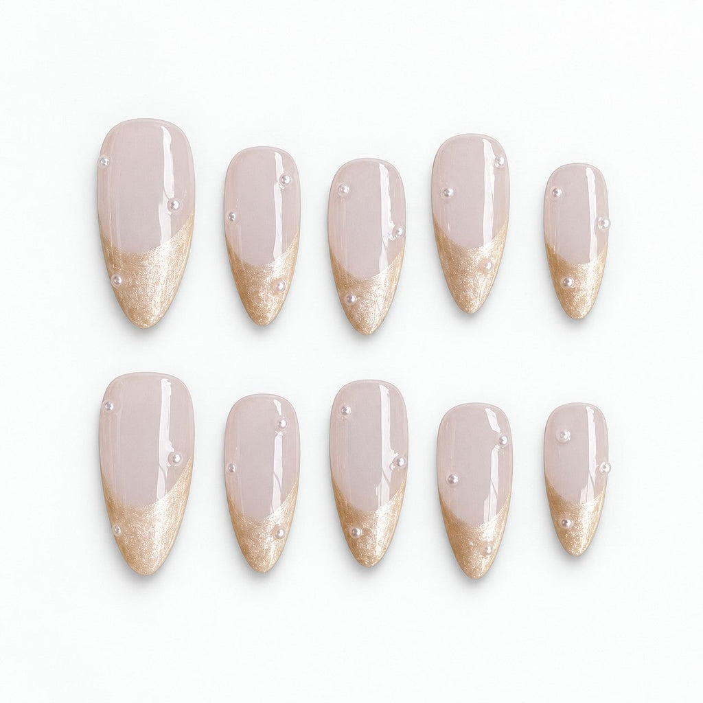 catalog: Medium almond press-on nails with a milky blush base, shimmering champagne French tips and small scattered pearls.