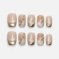 catalog: Short square press-on nails in sheer nude with cat-eye shimmer, mirrored gold French tips and small clear crystal and gold bead accents.