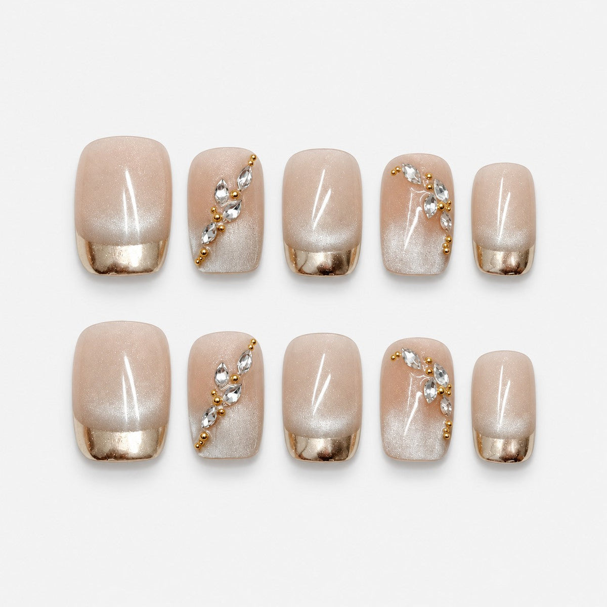 catalog: Short square press-on nails in sheer nude with cat-eye shimmer, mirrored gold French tips and small clear crystal and gold bead accents.