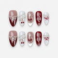 catalog: Medium almond press-on nails in burgundy, mauve and grey with painted white bows, silver bead strands and glossy red cherry charms.