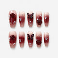 catalog: Coffin shaped press-on nails with a wine red to nude gradient, sculpted dark red roses, a carved butterfly, grey pearls and fine gold lines.