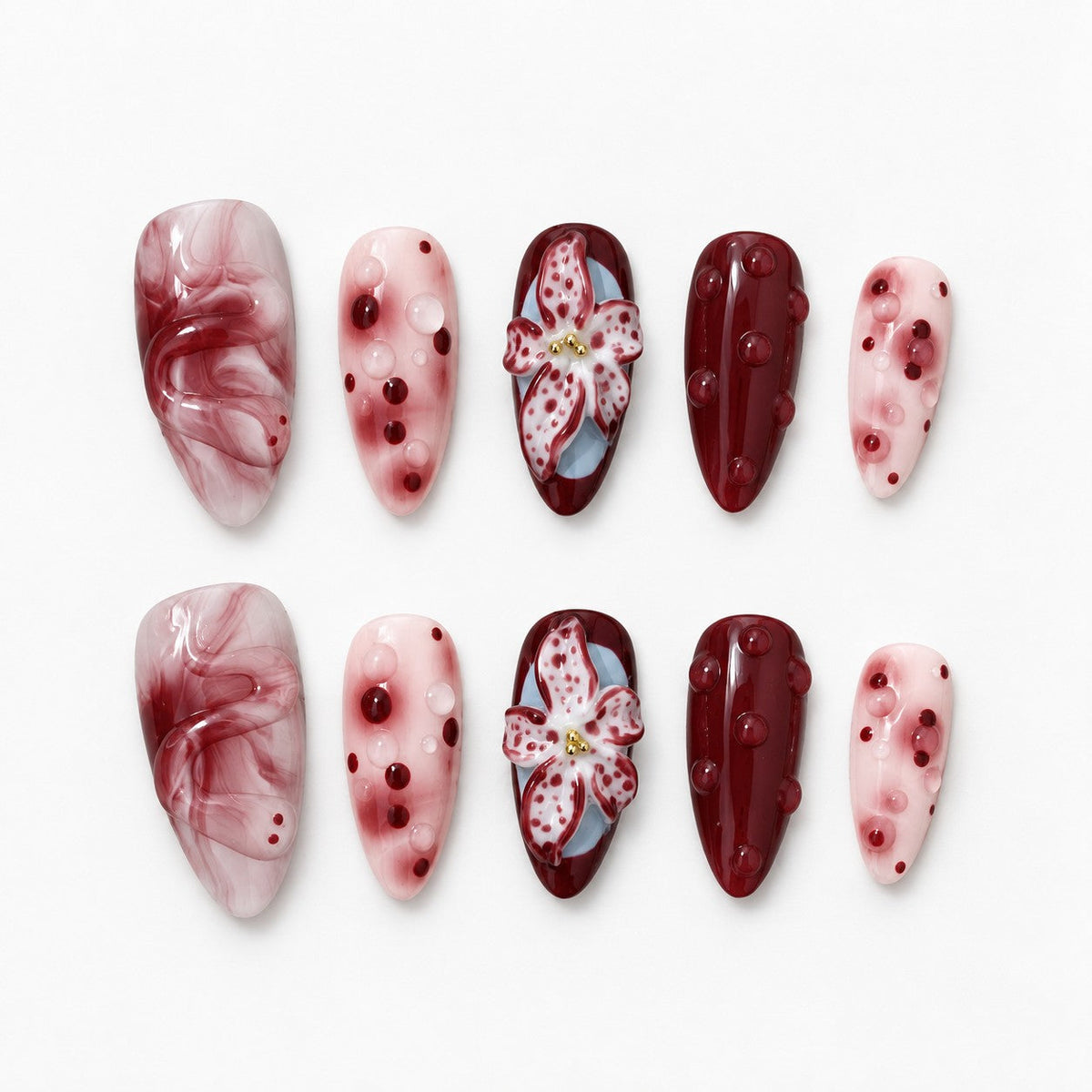 catalog: Medium almond press-on nails in wine red and blush pink with a sculpted three dimensional lily flower, marbled swirls and raised glossy dots.