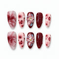 catalog: Medium almond press-on nails in wine red and blush pink with marbling, raised glossy dots and a sculpted hand-painted lily.