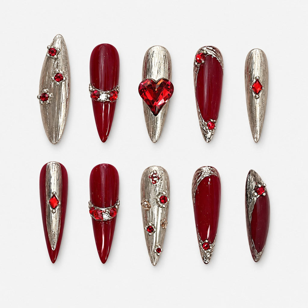 catalog: Long stiletto nails in deep red and brushed silver with a faceted red heart stone and scattered red crystals.