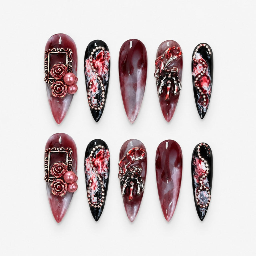 catalog: Long stiletto press-on nails in blood red marble with sculpted roses, pearls, rose gold frames, silver skeleton hands and glossy black tips.