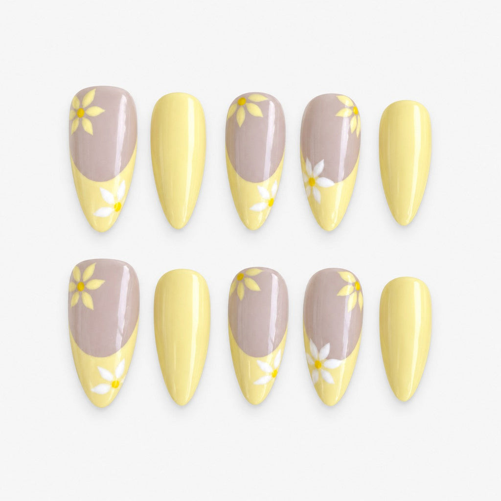 catalog: Long almond press-on nails with a pale yellow French tip over a greige base and small hand painted white and yellow daisies.