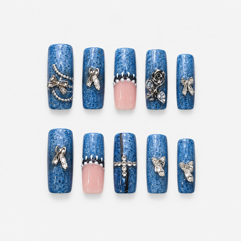 catalog: Long square press-on nails in speckled denim blue with sheer pink accents, silver rose and bow charms, pearls and small crystals.