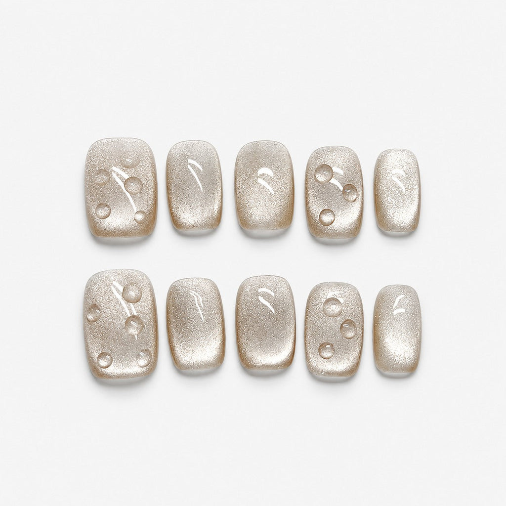 catalog: Short square press-on nails in frosted champagne pearl with small raised clear droplets.