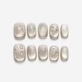 catalog: Short square press-on nails in frosted champagne pearl with small raised clear droplets.