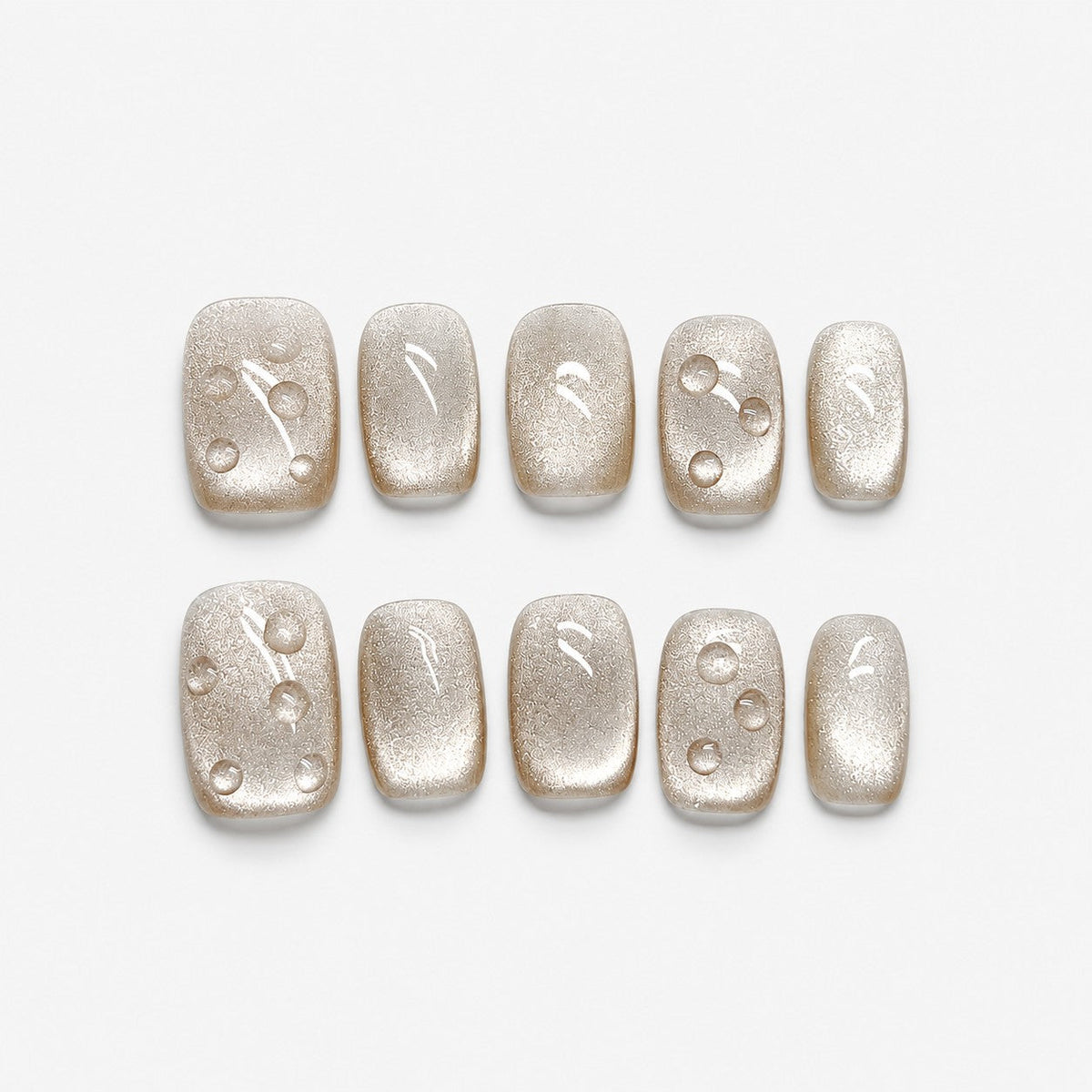 catalog: Short square press-on nails in frosted champagne pearl with small raised clear droplets.