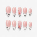 catalog: Long almond press-on nails with a sheer pink base, black and white polka dot tips and small sculpted pink flowers with gold centres.
