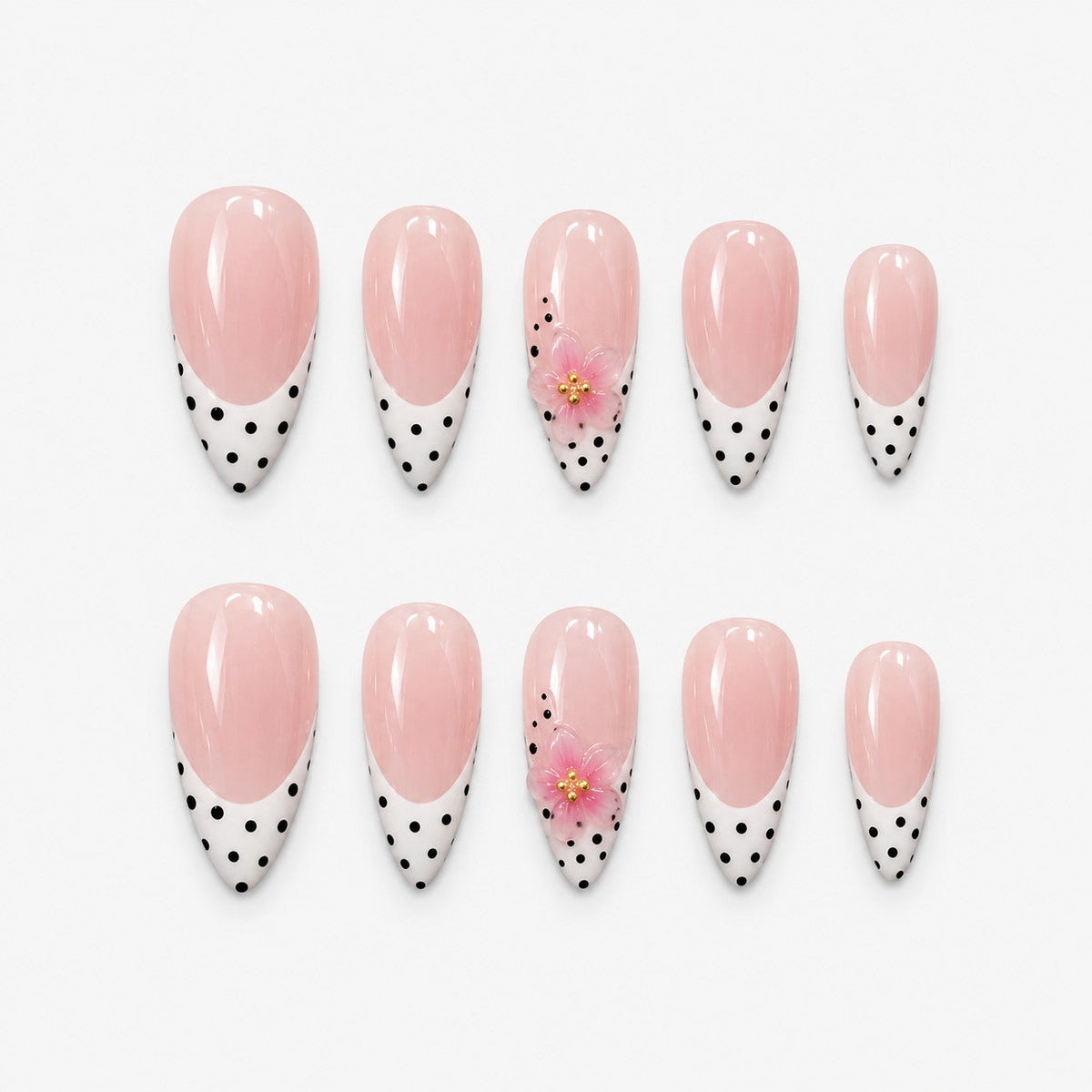 catalog: Long almond press-on nails with a sheer pink base, black and white polka dot tips and small sculpted pink flowers with gold centres.