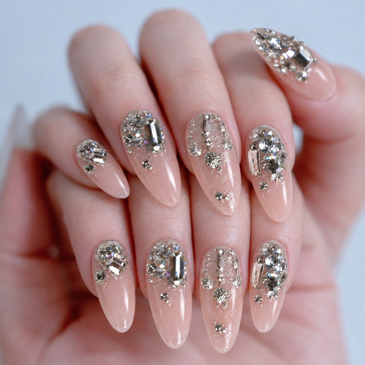 hand: Long square press-on nails with a bare clear base and dense clusters of clear crystals across the tips.
