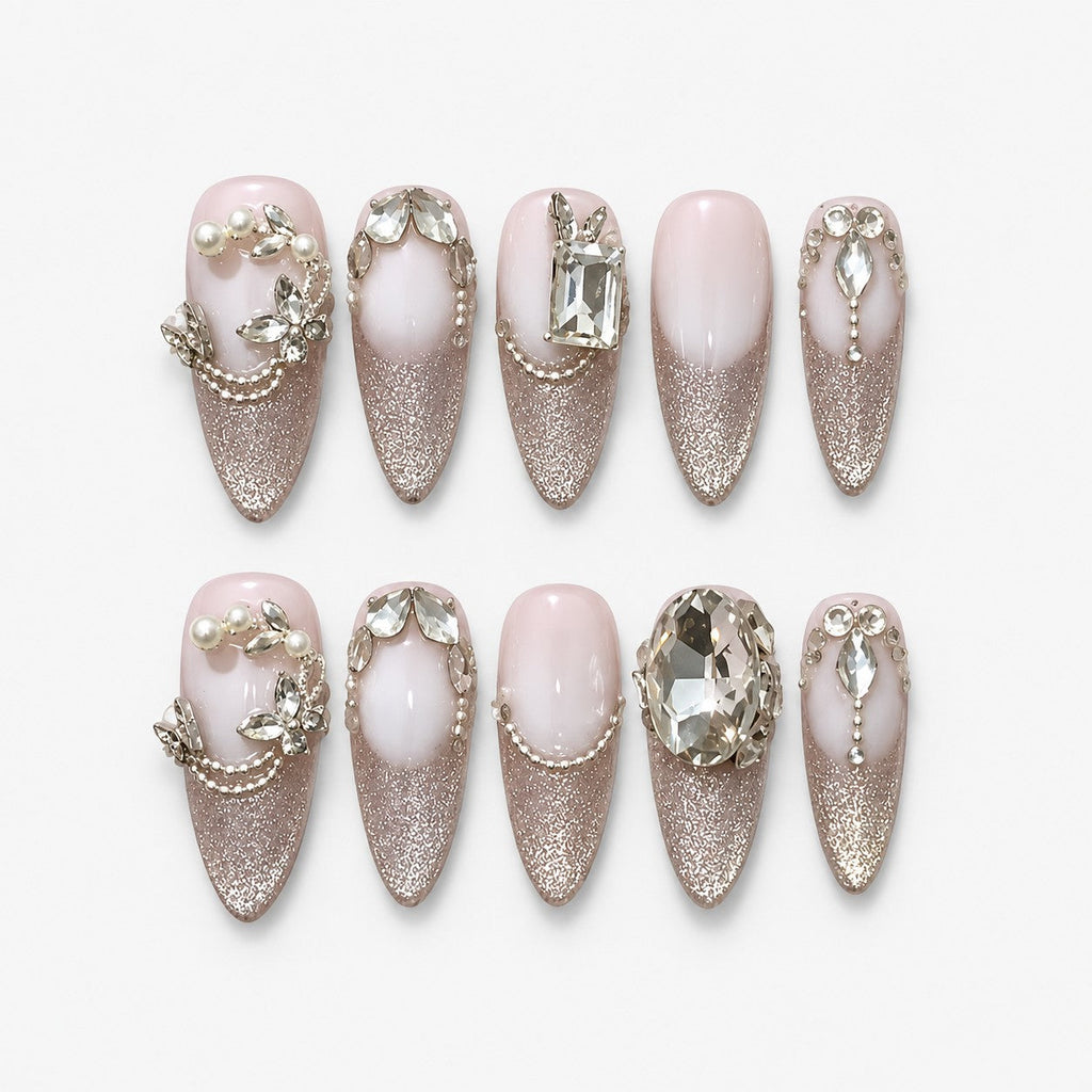 catalog: Long almond press-on nails with milky pink bases, silver cat-eye shimmer, clear faceted crystals, sculpted leaf vines and small pearls.