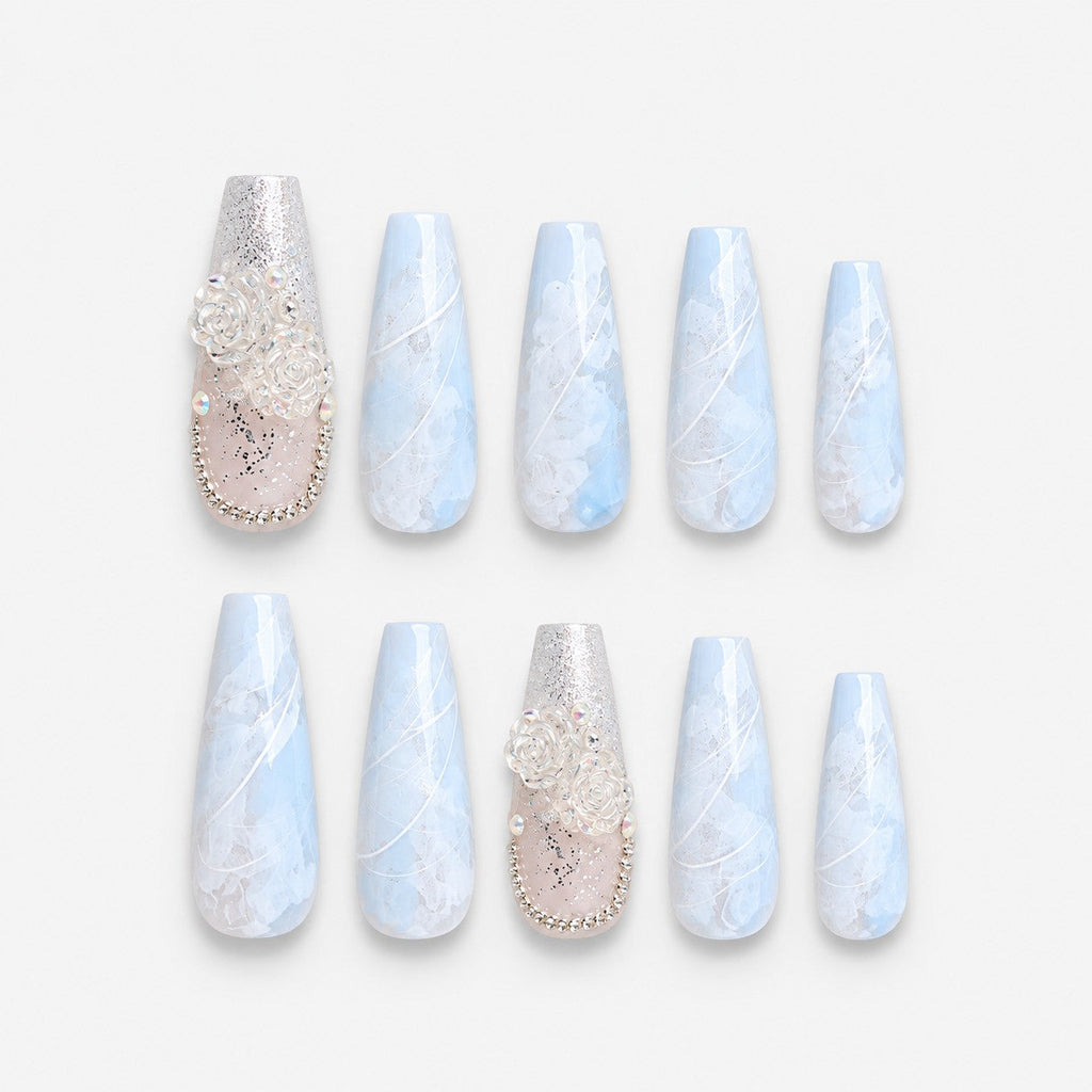 catalog: Long coffin press-on nails in blue and white marble with silver line detail and two accent nails holding sculpted white roses and crystals.