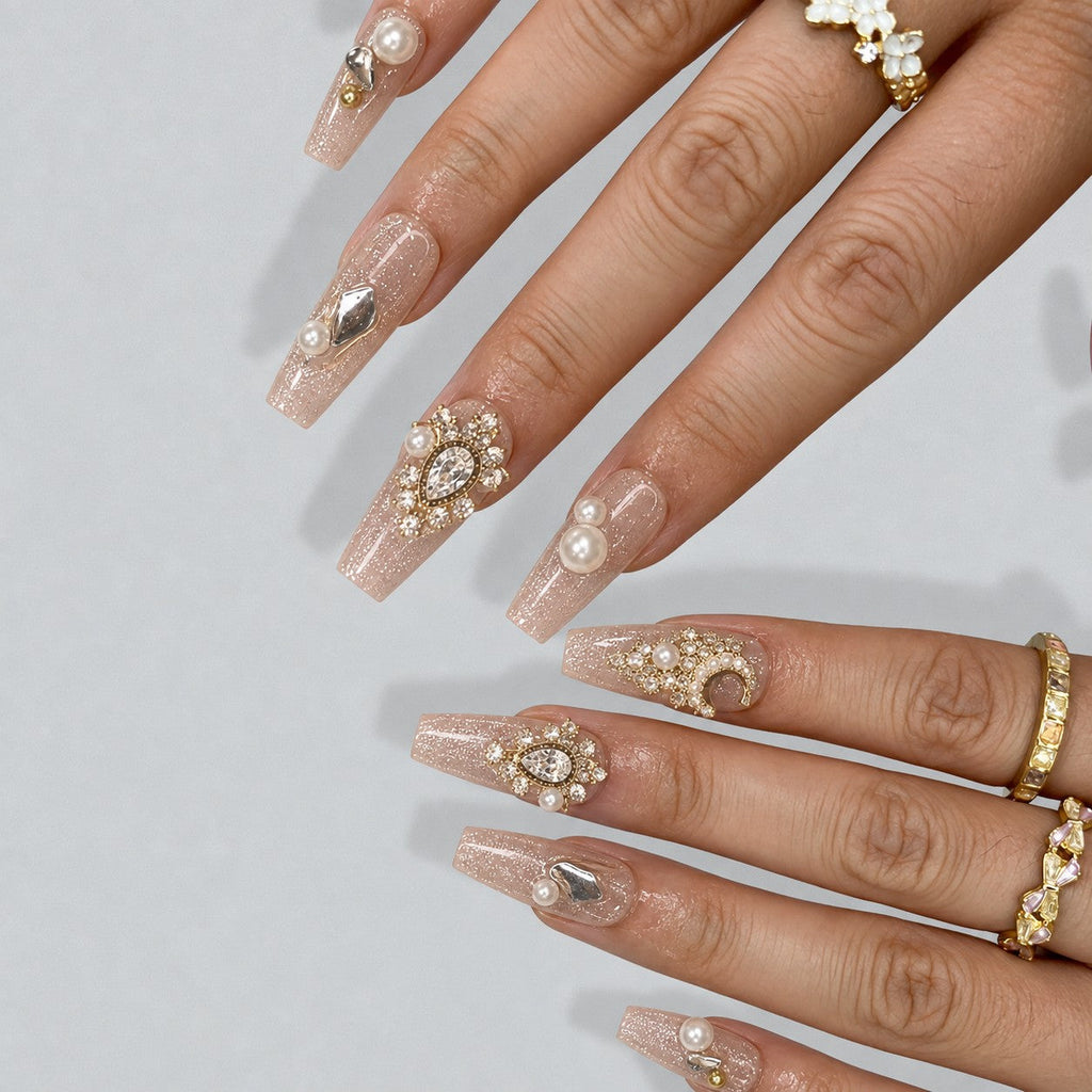 hand: Long clear coffin nails with silvery glitter, raised cream pearls and clear faceted crystal stones.