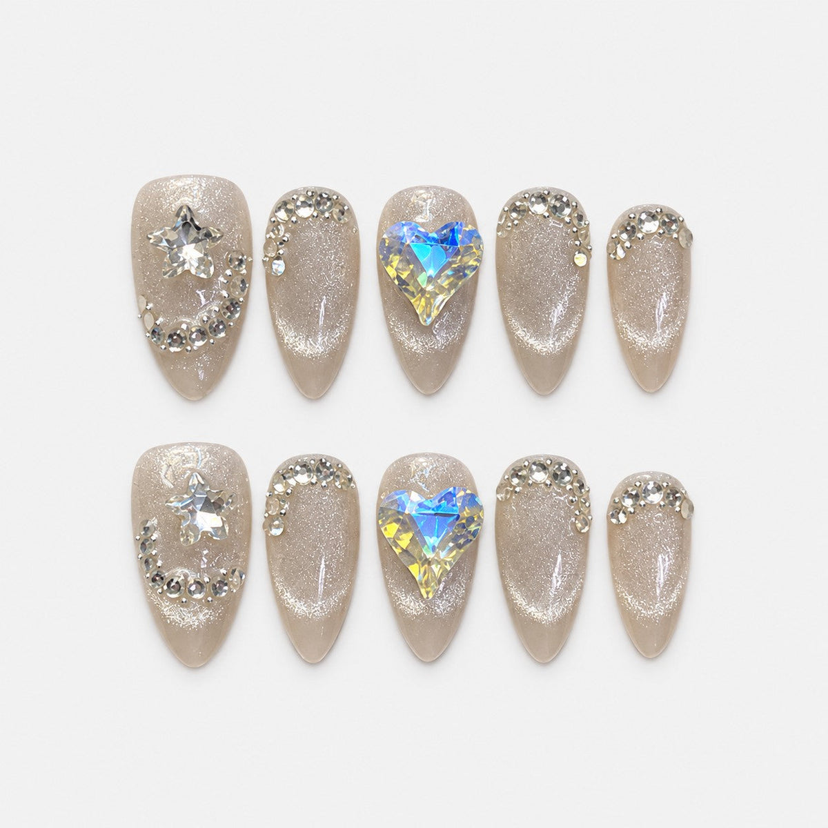 catalog: Medium almond press-on nails in icy greige cat-eye shimmer with clear crystal curves, a star gem and a large iridescent heart gem.