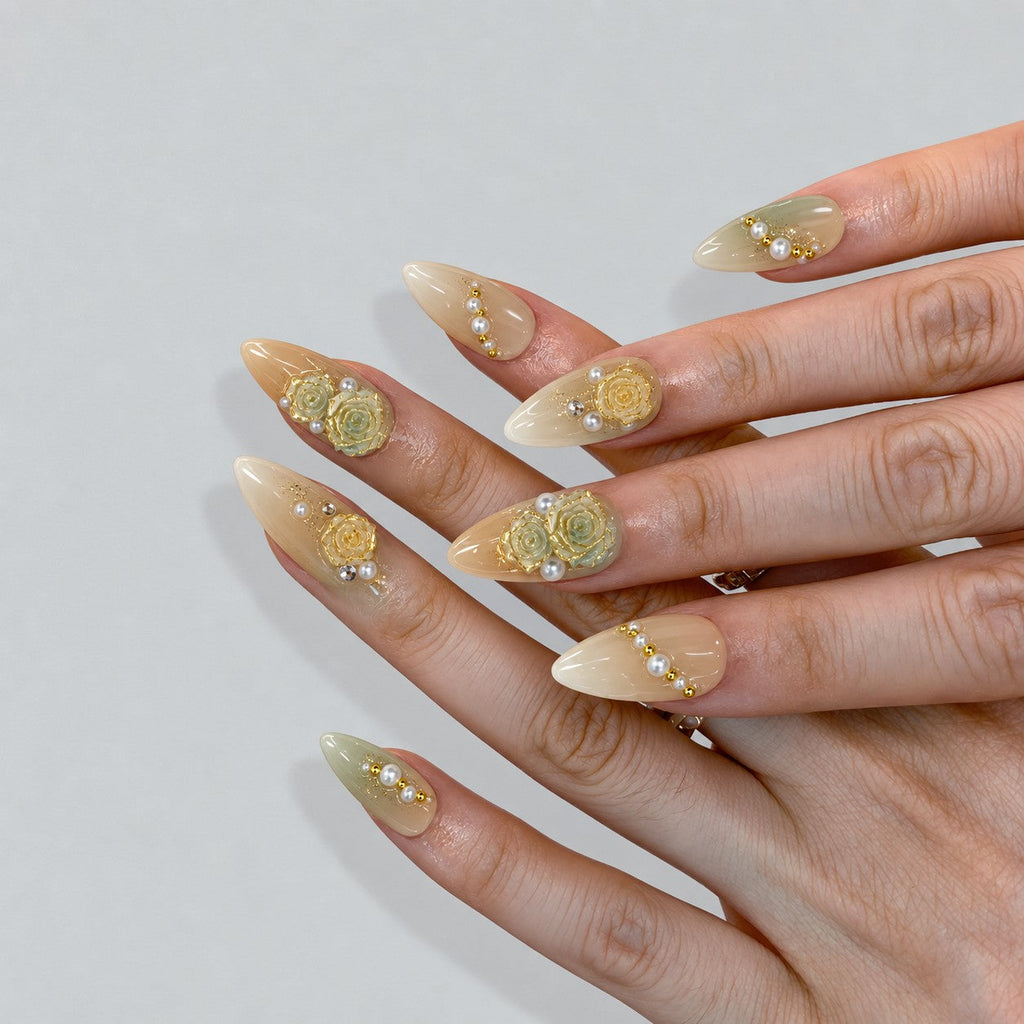 hand: Medium almond nails in cream and pale sage ombre with sculpted yellow and mint roses, gold leaf accents and strands of ivory pearls.