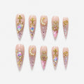 catalog: Long stiletto press-on nails in clear pink glitter with gold cross charms, a pearl crescent moon and large iridescent heart-shaped stones.
