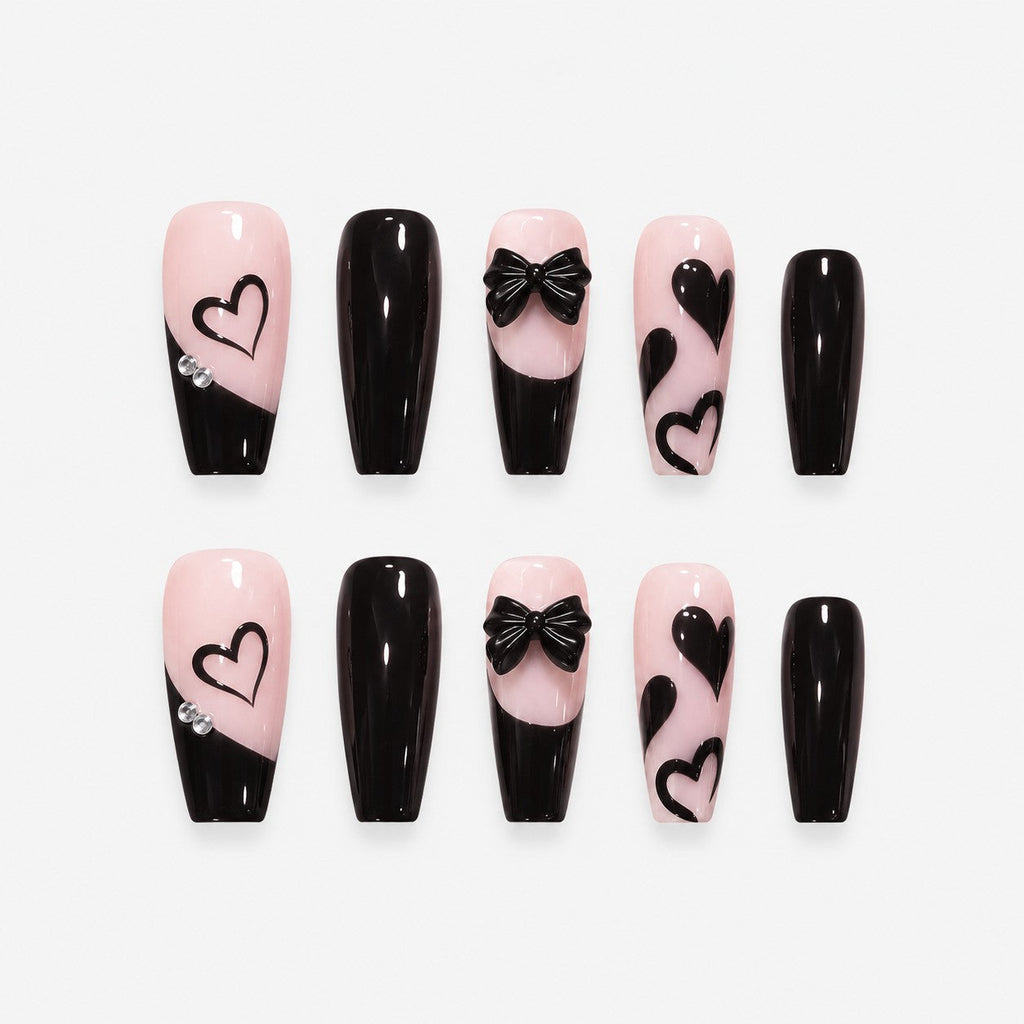 catalog: Long coffin press-on nails in near black over soft pink with slanted French tips, painted hearts and a sculpted black bow.