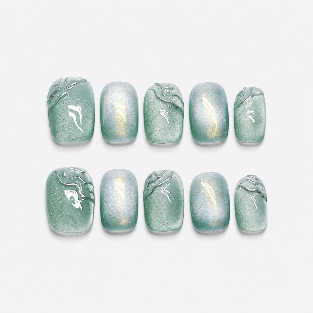 catalog: Short square press-on nails in sage green with a pearly cat-eye shimmer and raised clear brushstroke detail.
