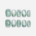 catalog: Short square press-on nails in sage green with a pearly cat-eye shimmer and raised clear brushstroke detail.