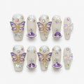 catalog: Medium coffin press-on nails in milky translucent white with purple 3D butterflies, a faceted purple planet charm, an iridescent bow and aurora rhinestones.