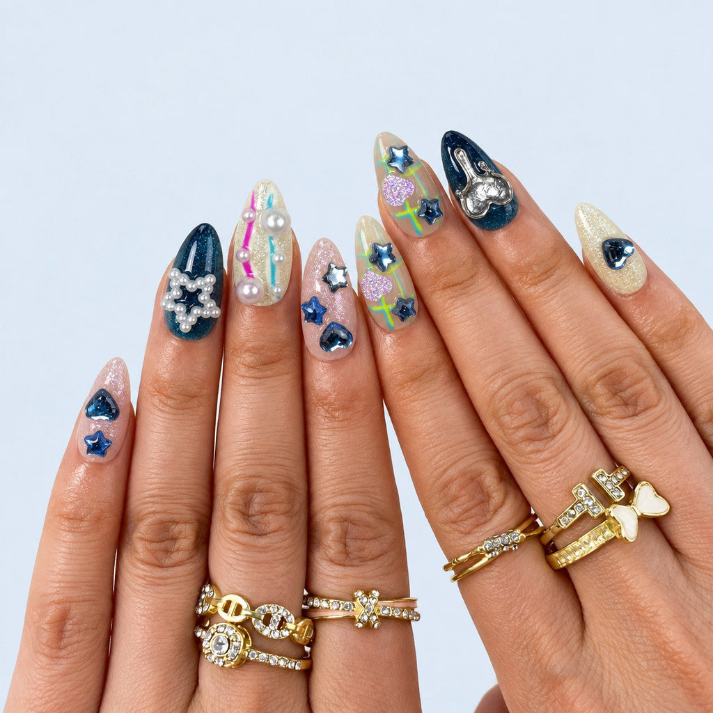 hand: Medium almond press-on set mixing deep teal cat-eye nails, silver starbursts, chrome hearts, pearl star charms and neon line art.