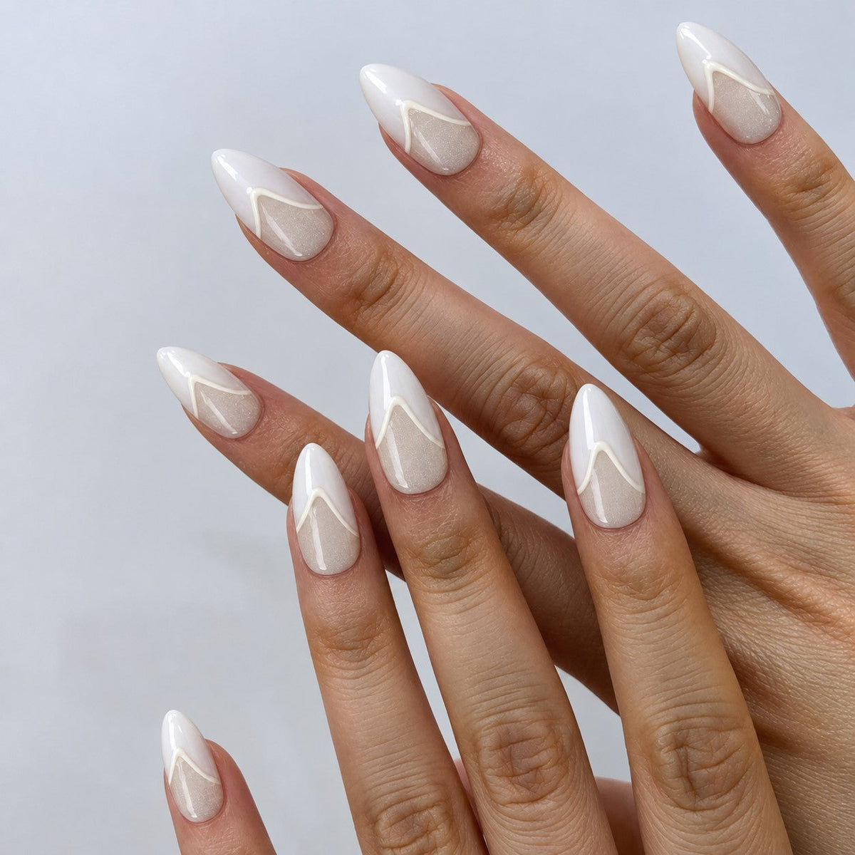 hand: Medium almond press-on nails in pearly off-white with a raised white chevron French tip and a high-gloss finish.