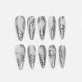 catalog: Long almond press-on nails in milky white with raised liquid silver chrome sculpted along the edges and tips.
