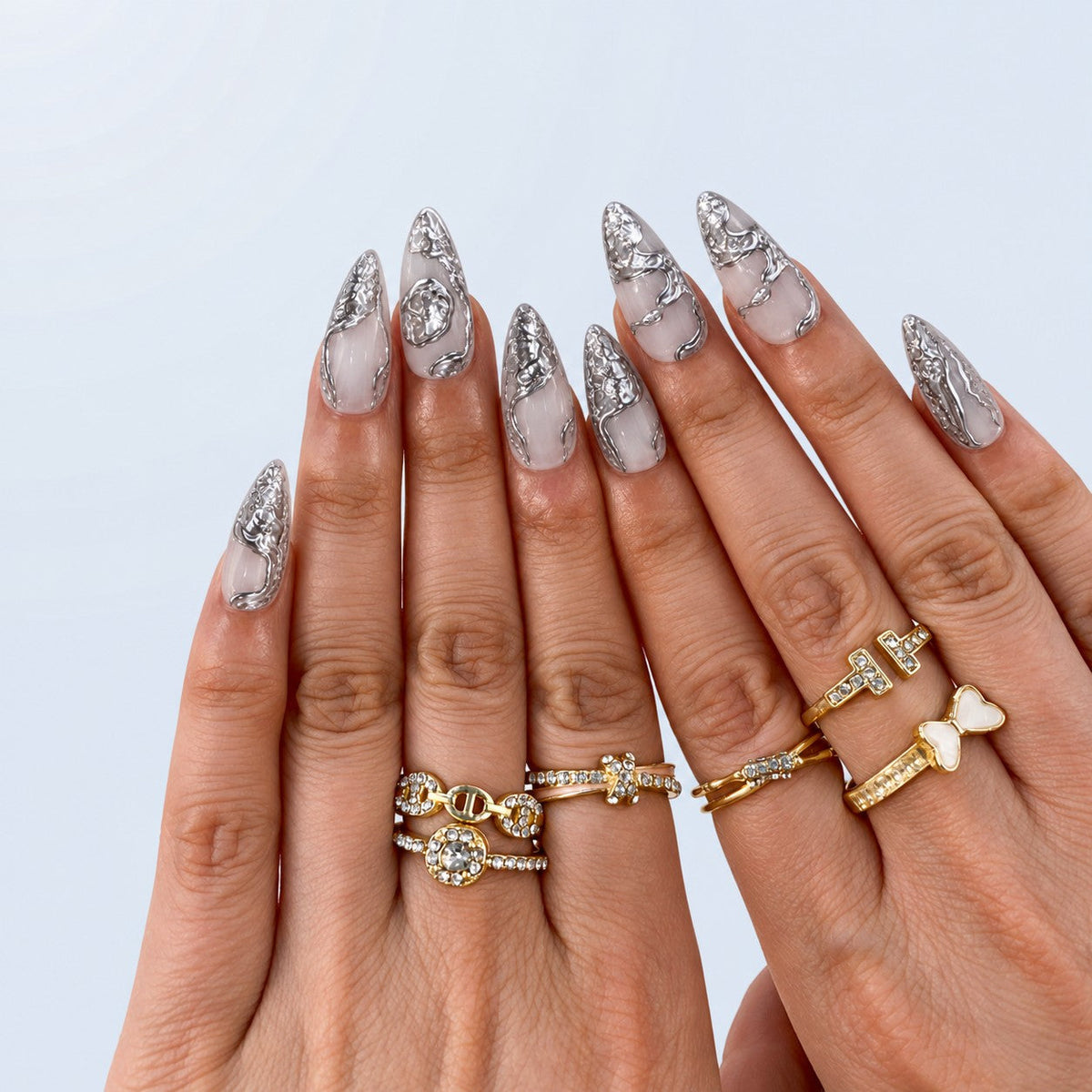 hand: Long almond press-on nails in milky white with raised liquid silver chrome sculpted along the edges and tips.