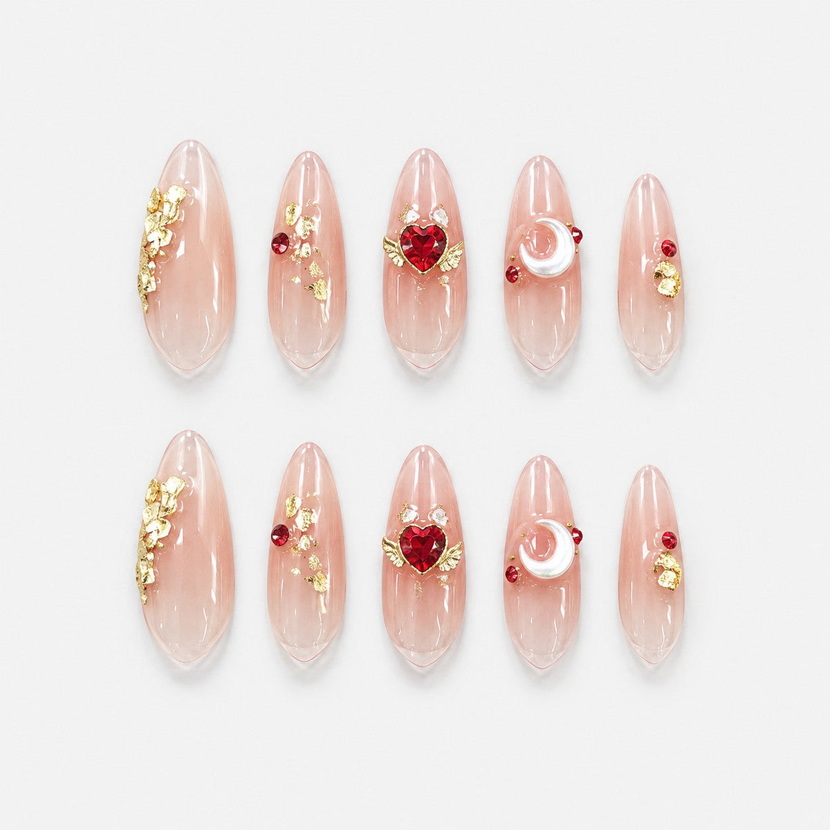 catalog: Long almond press-on nails in clear nude with gold leaf flecks, a red heart crystal with gold wings, and a pearl crescent moon charm.