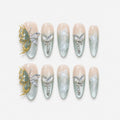 catalog: Long almond press-on nails with nude to sage green cat-eye gradient, white painted butterflies, crystals, pearls and a raised gold and stone butterfly charm.