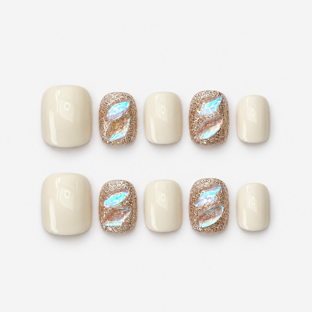 catalog: Short square nails in creamy off white with two rose gold glitter accent nails holding iridescent aurora shards.
