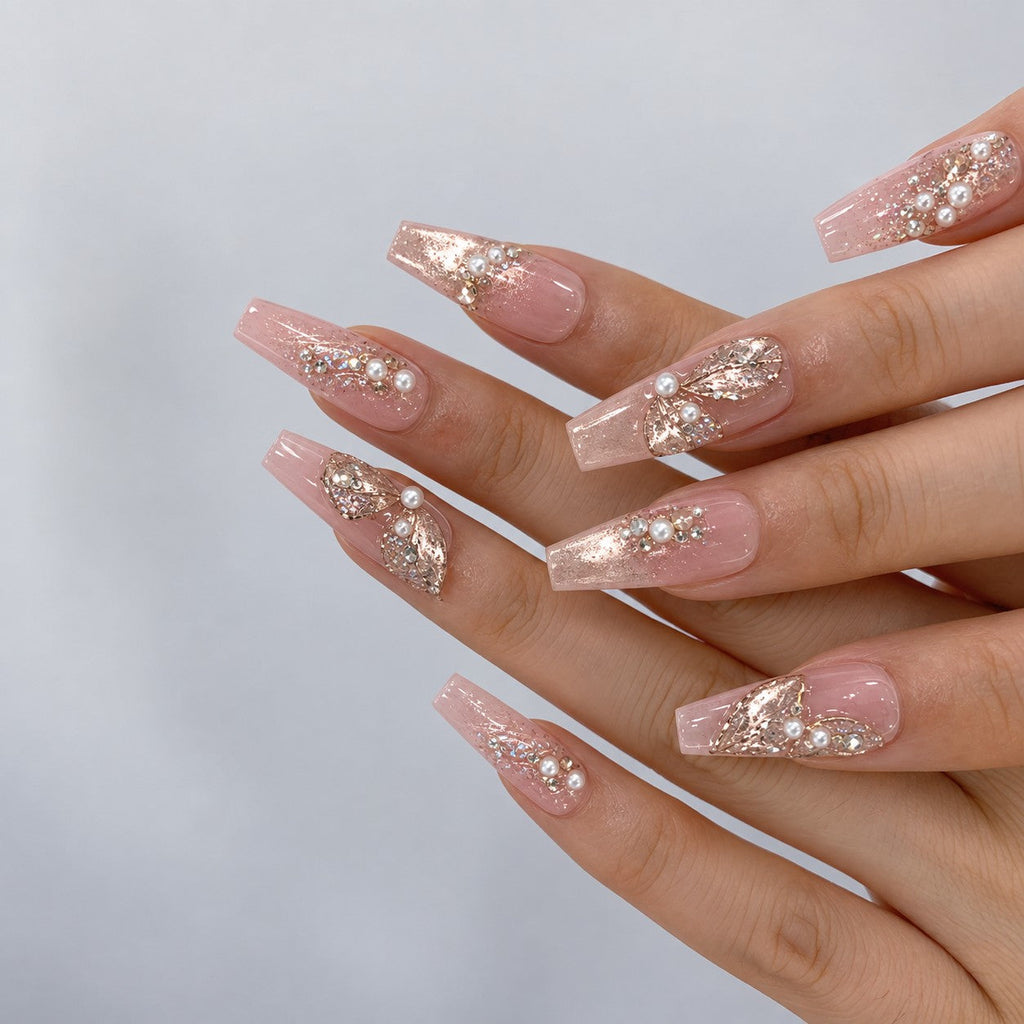 hand: Long pink sheer nails with sculpted glitter petals, small pearls and rhinestones over a shimmering base.