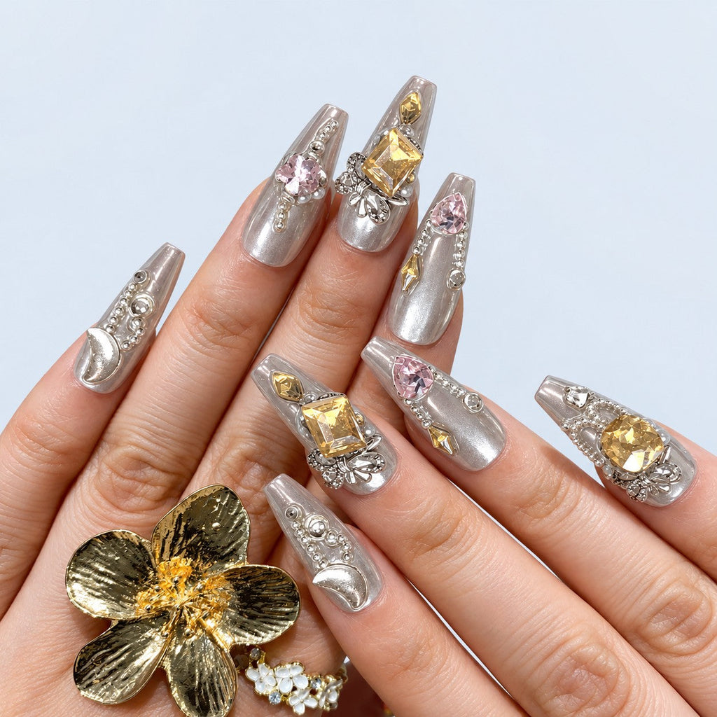 hand: Long coffin nails in pearly silver set with iridescent heart and square gems, silver bead chains and rhinestone bows.