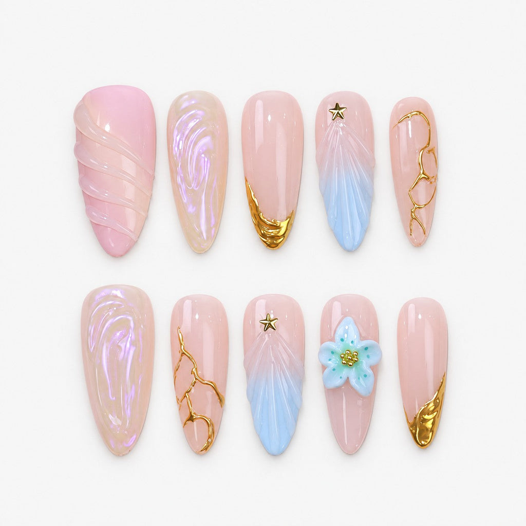 catalog: Almond press-on nails in soft pink with sculpted blue wings, a pale blue flower, gold vein lines, gold star studs and gold-dipped tips.