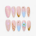 catalog: Almond press-on nails in soft pink with sculpted blue wings, a pale blue flower, gold vein lines, gold star studs and gold-dipped tips.