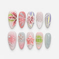 catalog: Long almond press-on nails in milky pink, green and grey with sculpted 3D lilies and blossoms, red painted petal veins and small white pearls.