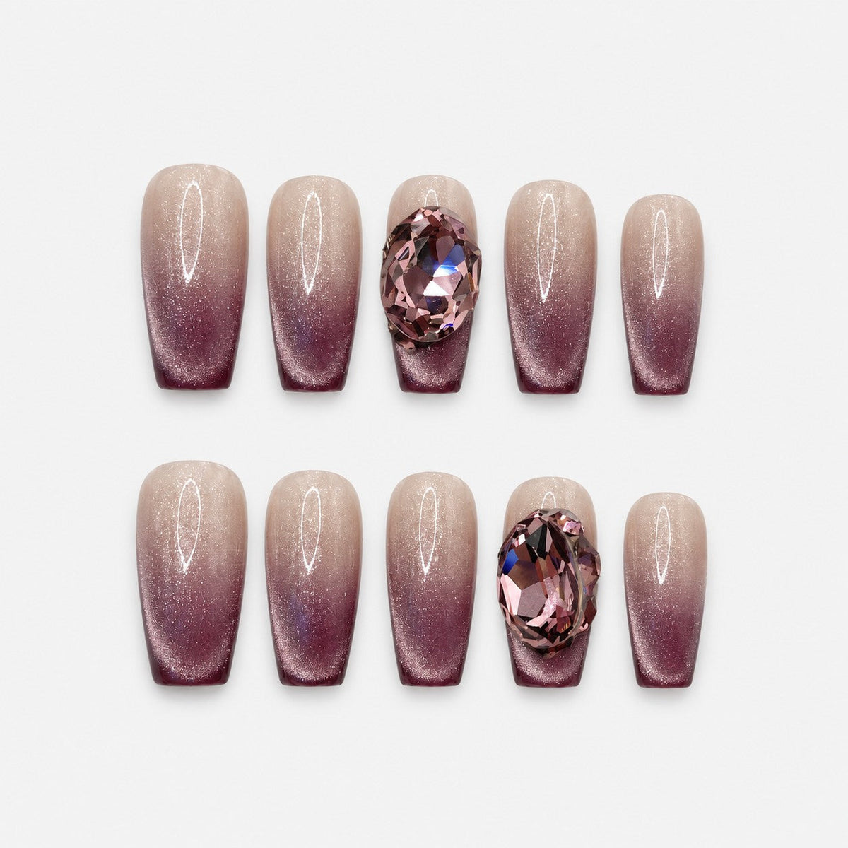catalog: Medium coffin-shaped press-on nails with a nude to plum cat-eye gradient and a large pink faceted crystal on one nail.