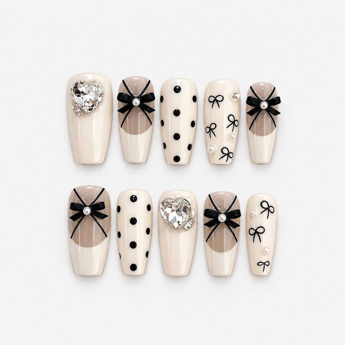 catalog: Medium coffin press-on nails in cream with sheer French tips, black satin bows, black polka dots and clear heart-shaped crystals.